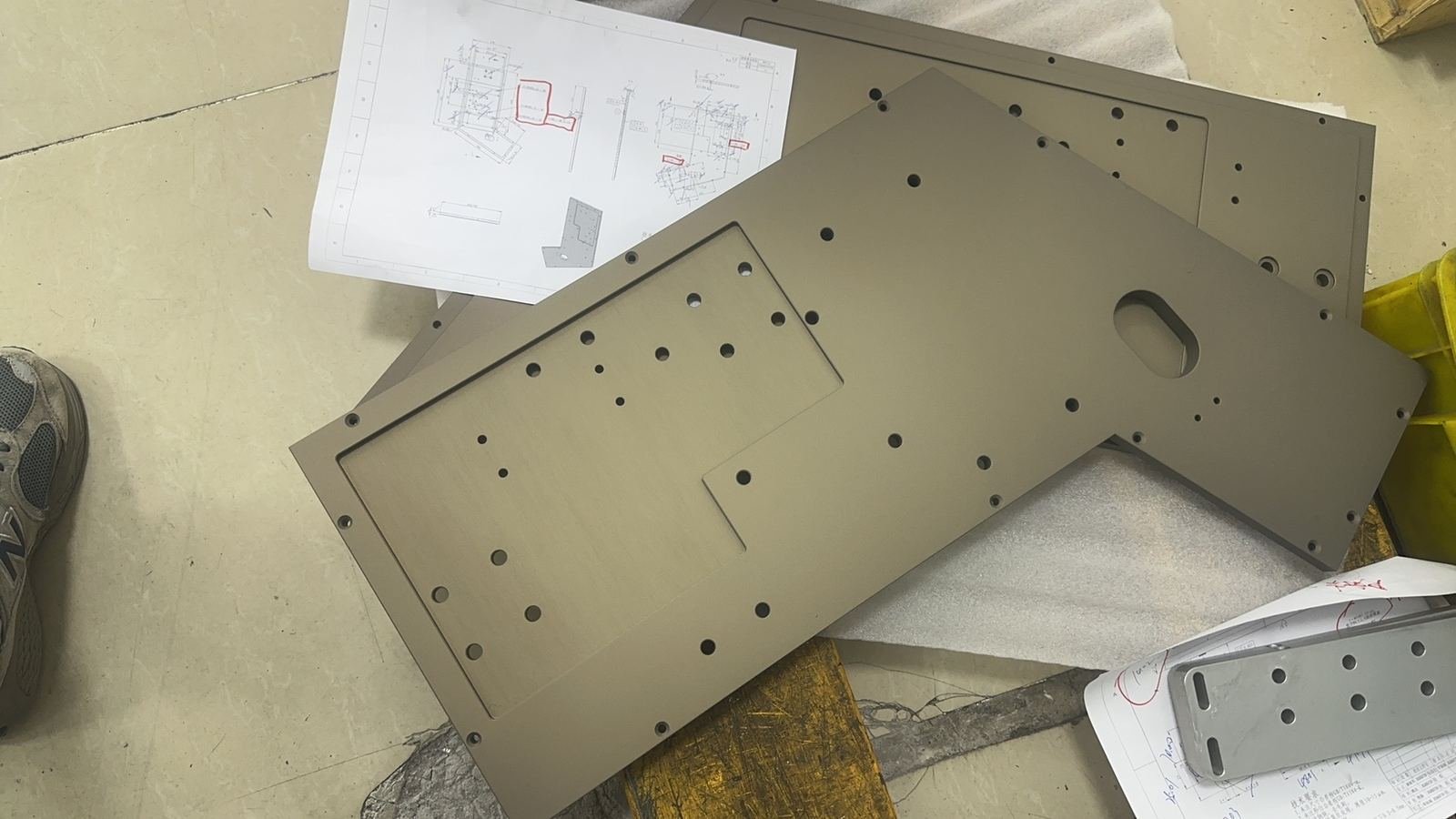 Prototype machined plate beside an engineering drawing
